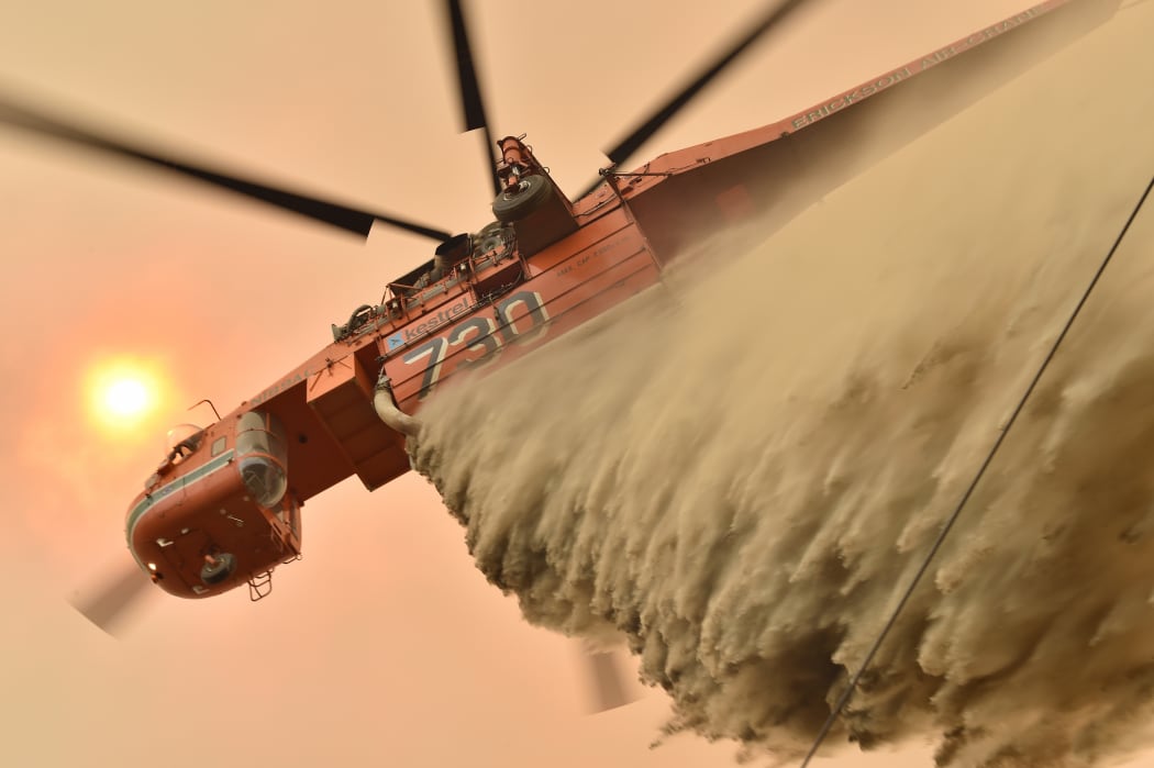 A helicopter drops fire retardent to protect a property in Balmoral 150km southwest of Sydney.