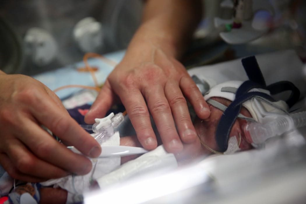 Father checking son's temperature at Wellington NICU