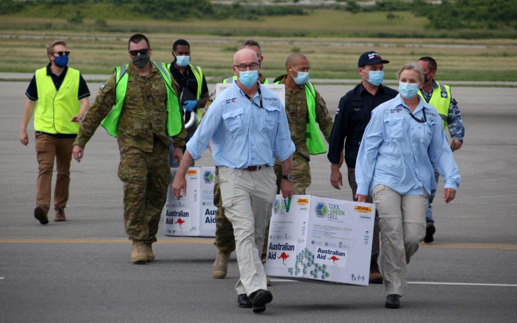 Australian officials carry boxes containing some 8,000 initial doses of the AstraZeneca vaccine following their arrival in Papua New Guinea.