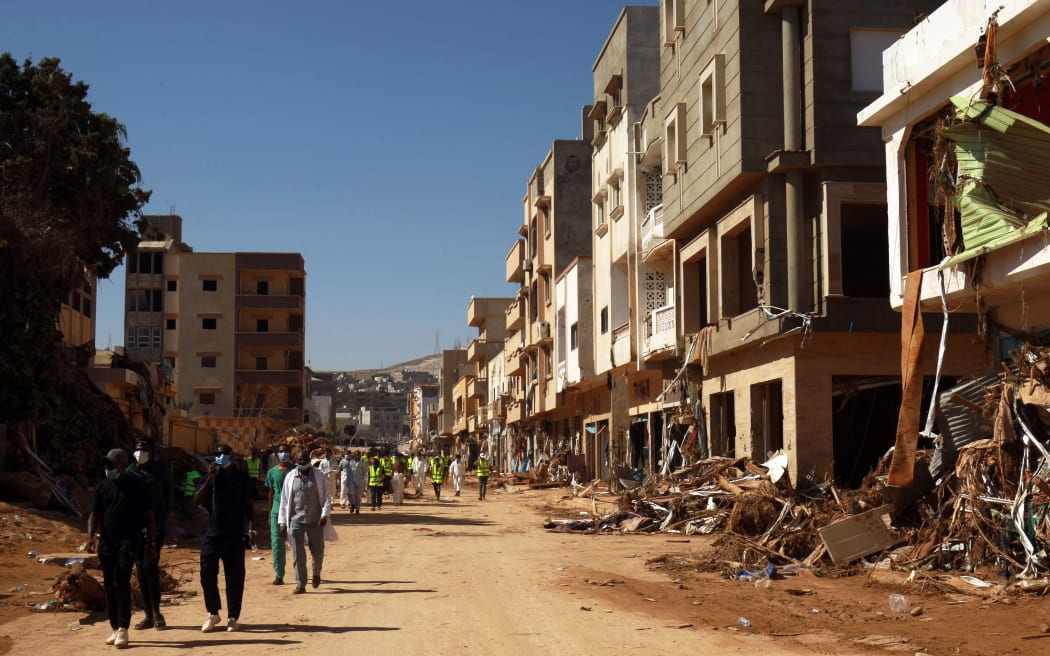 Volunteers pass damaged homes in Derna. Rescuers have been sifting through mud and rubble searching for people missing after the flash flood.