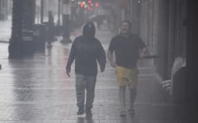 People walk on Canal Street in New Orleans, Louisiana on 29 August 2021 during Hurricane Ida.