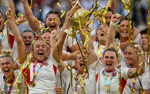 England's flanker Zoe Aldcroft and England's centre Megan Jones lift the winners trophy following the Women’s Rugby World Cup final between Canada and England at Twickenham, 2025.