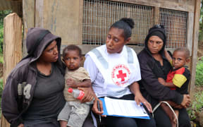 A Red Cross volunteer talks with two widows whose husbands were both killed in a landslide following the earthquake.