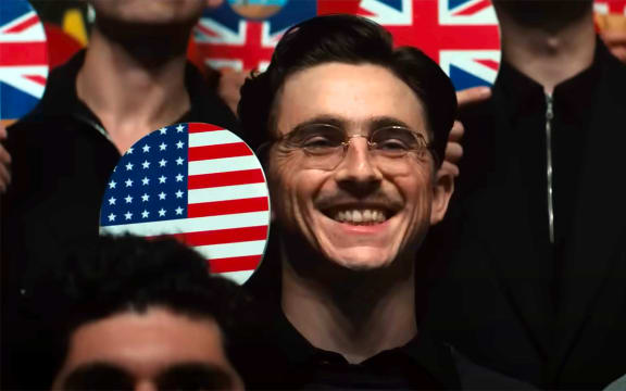 As Marty Supreme, Timothée Chalamet is a beaming young man holding up a ping-pong racquet with the American flag.