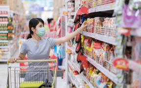 Young woman wearing protective face mask and  shopping in grocery or department store protect coronavirus inflection. social distancing, new normal and life under covid-19 pandemic
