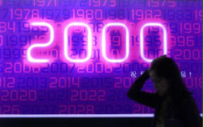 A woman walks past a billboard celebrating the coming year 2000 in Hong Kong.