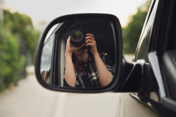 Private detective with camera spying from a car.