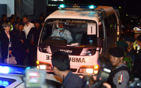 Australian Consul General for Bali Majell Hind (L in black coat) looks at the ambulance carrying a coffin bearing the body of one of the eight drug convicts.
