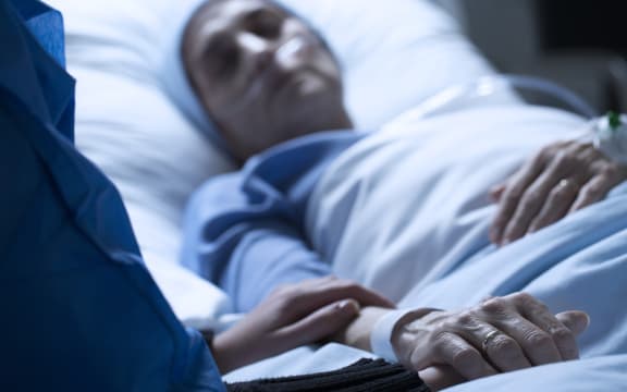 Young woman in hospice care, holding hands in hospital.