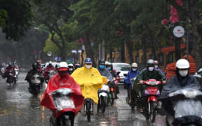 Motorists wearing face masks ride amid a downpour in Hanoi as Vietnam eased its nationwide social isolation effort to prevent the spread of the COVID-19.