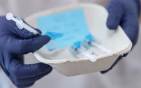 Gloved hands holding a tray with syringes with Comirnaty Covid-19 vaccine made by Pfizer/ BioNTech.
Photo: Johan Nilsson / TT / Code 50090 (Photo by JOHAN NILSSON / TT NEWS AGENCY / TT News Agency via AFP)