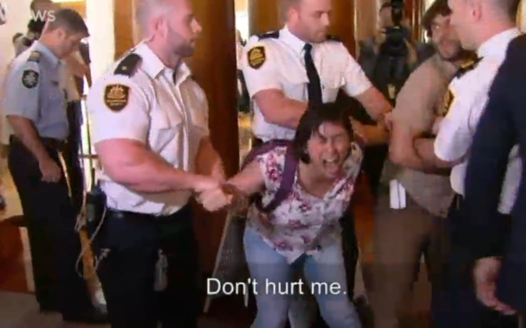 A protester is forcibly removed from the building by security staff.