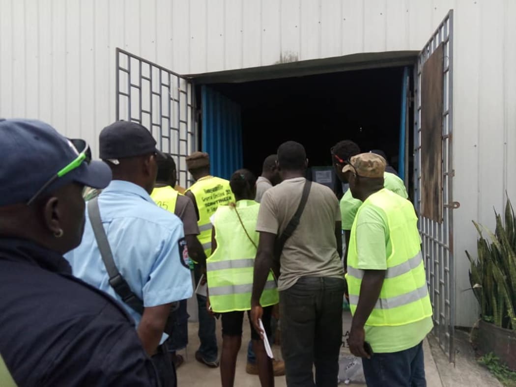 Observers and staff watch the transportation of ballot boxes