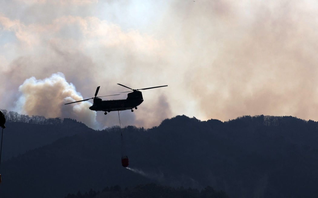 Japan Self-Defense Force helicopter collects seawater from Ofunato Port and heads to the forest fire site in Ofunato City in Iwate Prefecture, northern region of Japanese Archipelago, on March 2, 2025. The wildfire broke out on February 26th, and firefighting efforts including Japan Self-Defense Forces have continued. Approximately 4,600 people have been asked to evacuate, and about 1,000 people were taking shelter in evacuation centers. At least 84 houses and other buildings were damaged. About 1,400 hectares have burned so far, and at least 84 houses damaged.    ( The Yomiuri Shimbun ) (Photo by Hiroto Sekiguchi / Yomiuri / The Yomiuri Shimbun via AFP)