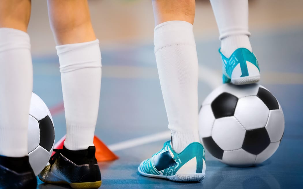 Indoor soccer players training with balls. Indoor soccer sports hall. Football futsal player, ball, futsal floor. Sports background. Futsal league. Indoor football players with classic soccer ball.