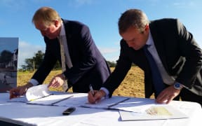Housing Minister Nick Smith and Fletcher Building CEO Steven Evans sign the contract to build 196 homes on Moire Rd.