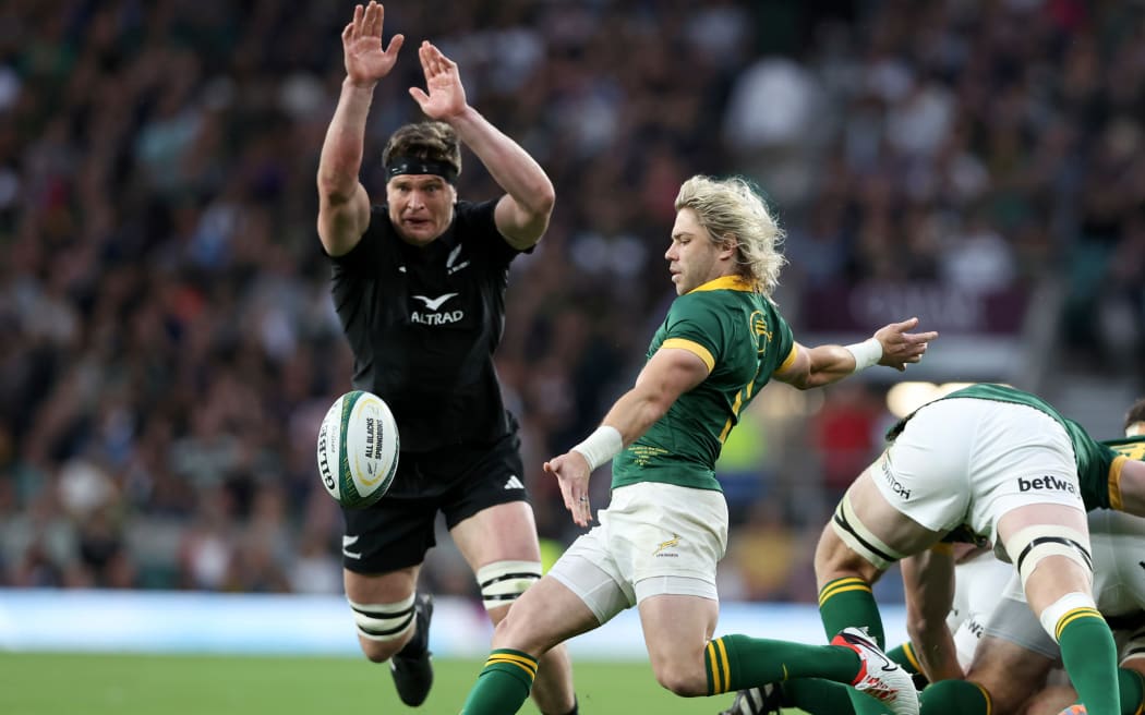 South Africa halfback Faf de Klerk makes a clearing kick as All Black Scott Barrett bears down on him during New Zealand's loss at Twickenham.