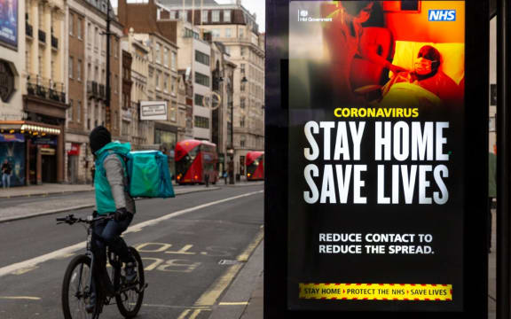 A delivery man on his bicycle is seen riding by the NHS 'Stay Home' poster as the UK's government introduced strict Coronavirus restrictions earlier this month due to sharp increase in numbers of Covid-19 cases in UK o)