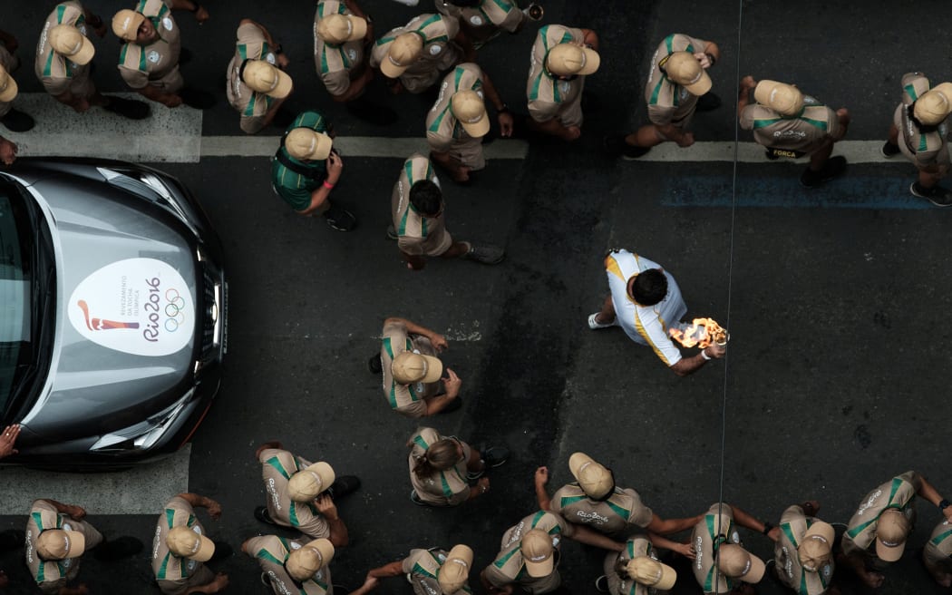 An Olympic torch bearer is escorted by security in Rio de Janeiro.