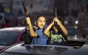 Children hold up guns to celebrate the Gaza Strip ceasefire.
