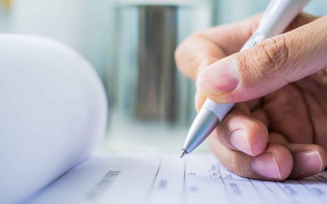 Hand with pen over application form on blure water glass background