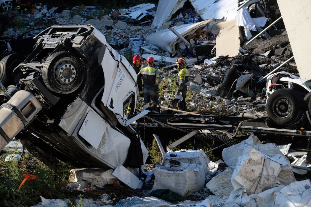 Rescuers inspect the rubble and wreckages by the Morandi motorway bridge.