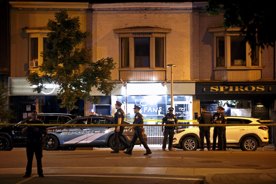 Toronto Police officers walk the scene at Danforth St. at the scene of a shooting in Toronto, Ontario, Canada on July 23, 2018.