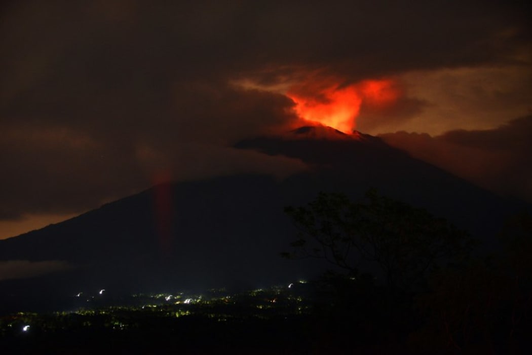 A pre-dawn view shows the erupting Mount Agung volcano.