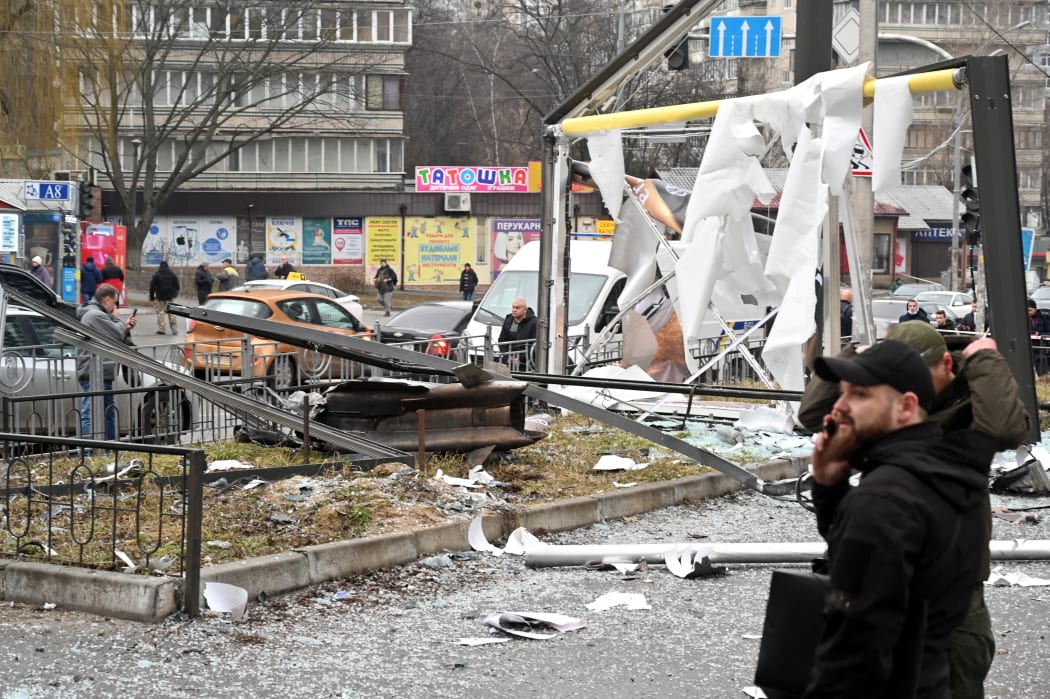 Police and security personnel inspect gather by the remains of a shell landed in a street in Kyiv on February 24, 2022.