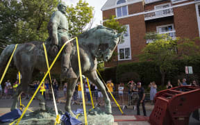 People watch as the statue of Confederate General Robert E. Lee is removed from a park in Charlottesville, Virginia.