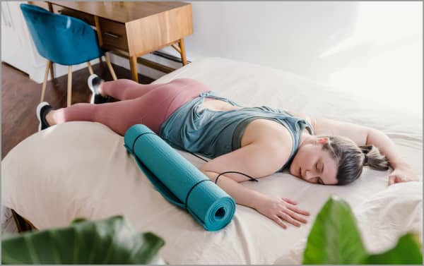 Woman sleeping in exercise gear on a bed.
