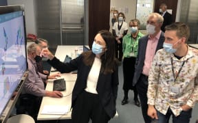 Jacinda Ardern points at a biological molecule on a screen at ESR as scientists look on
