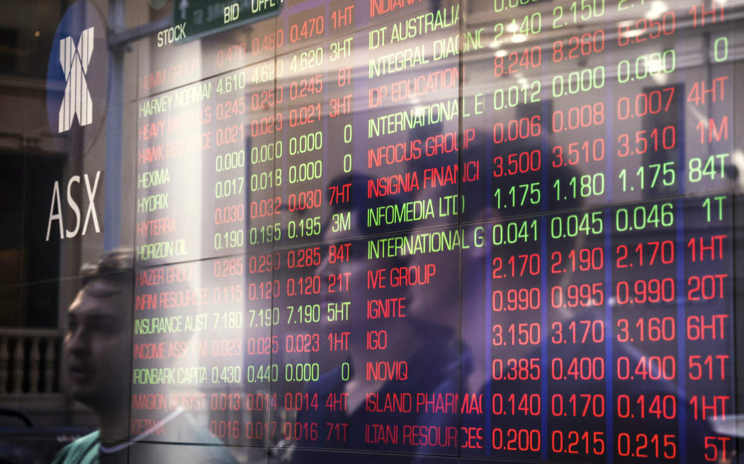 Pedestrians are reflected on a window as they walk past a board displaying stock prices at the Australian Stock Exchange in Sydney.