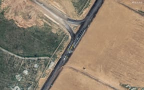 This handout satellite picture taken and released by Maxar Technologies on 15 February, 2024 shows machinery building a wall along the Egypt-Gaza Strip border in Rafah, Egypt.