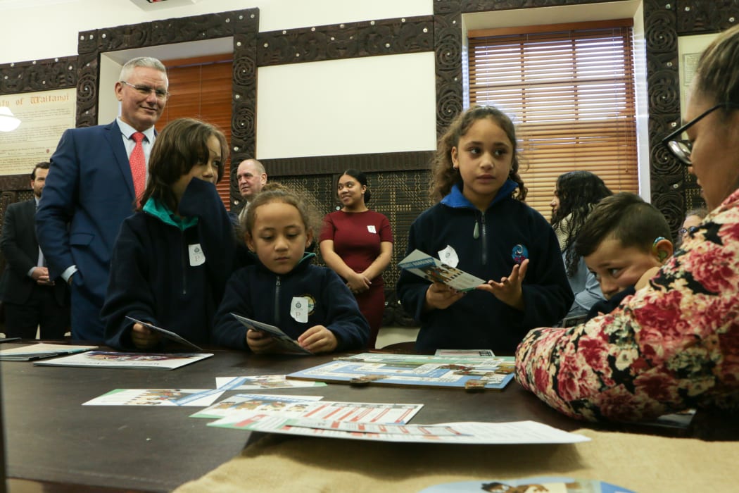 Te Kura Kaupapa Māori o Ngā Mokopuna students playing the board game Ngāti Ranginui at Parliament as associate education minister Kelvin Davis looks on.