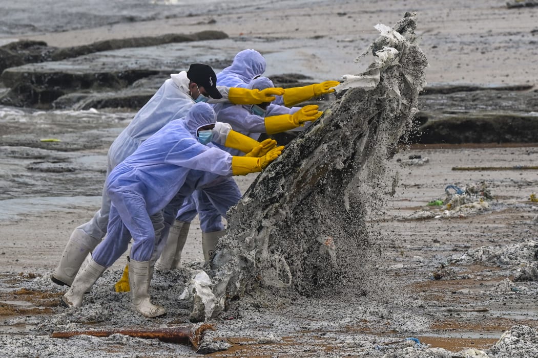 Sri Lankan Navy soldiers work to remove debris washed ashore from the burning X-Press Pearl on a beach in Colombo on 28 May, 2021.