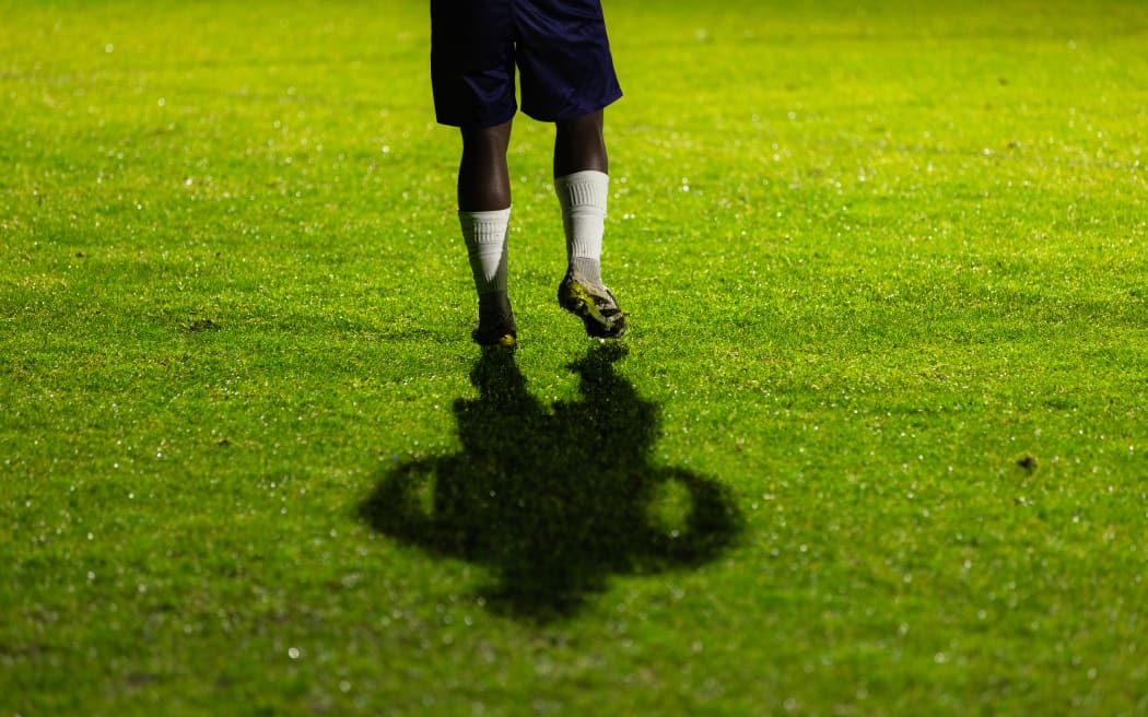 A football player warms up on the side of the field during a night game.