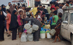 Palestinians queue to fill up on drinking water in the sweltering heat in the Mawasi area of Khan Yunis in the southern Gaza Strip on 12 August, 2025.