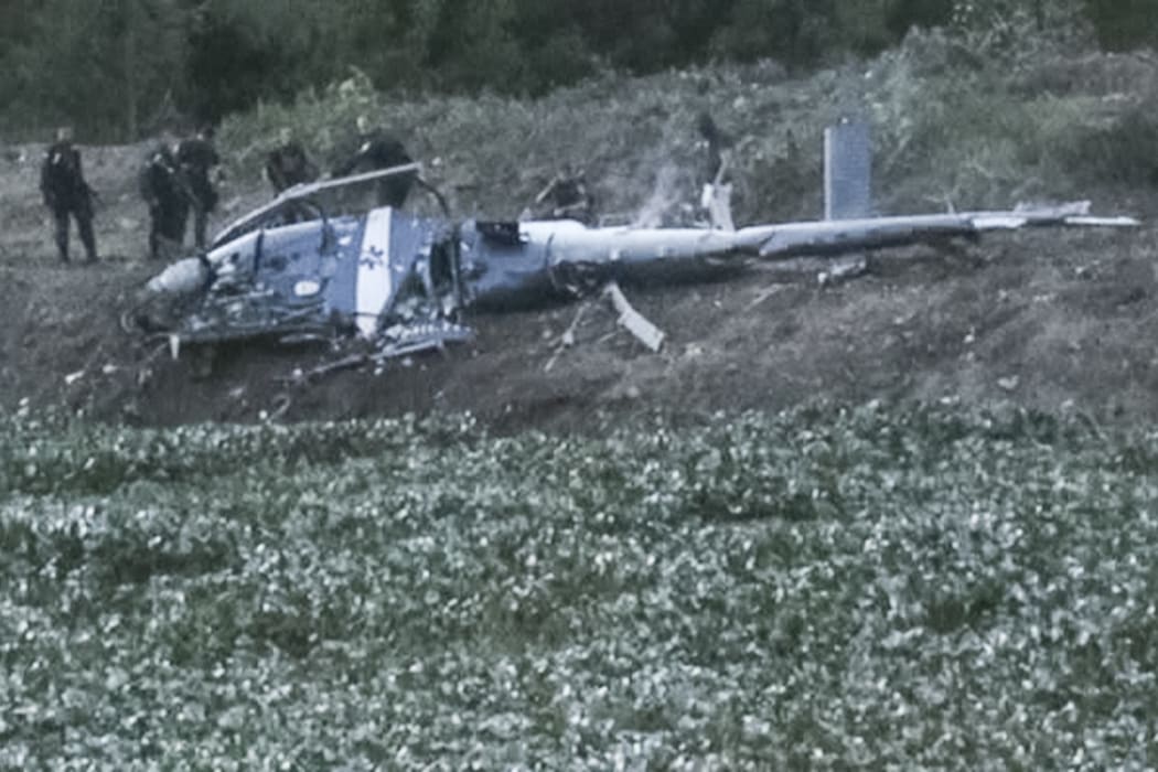 Police officers investigate the wreckage of the helicopter that was shot down during a raid on drug dealers.