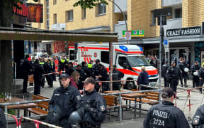 This photo taken on June 16, 2024 shows an ambulance car as German police officers close off an area at the Reeperbahn in the St Pauli district in Hamburg, northern Germany, after police shot and injured a man armed with a pickaxe and molotov cocktail. Police shot and injured a man who threatened them with an axe and a Molotov cocktail ahead of a Euro 2024 match in Hamburg on Sunday, German authorities said. The incident triggered a "major operation" in the city's St Pauli district, police said on X, formerly Twitter. A 39-year-old German man has been identified as a suspect, police sources told AFP. There was no indication of a link to the Euro 2024 clash between Poland and the Netherlands that took place later on Sunday, a police spokesman said. (Photo by Steven Hutchings / dpa / AFP) / Germany OUT