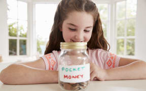 A photo of a Girl Saving Pocket Money In Glass Jar At Home