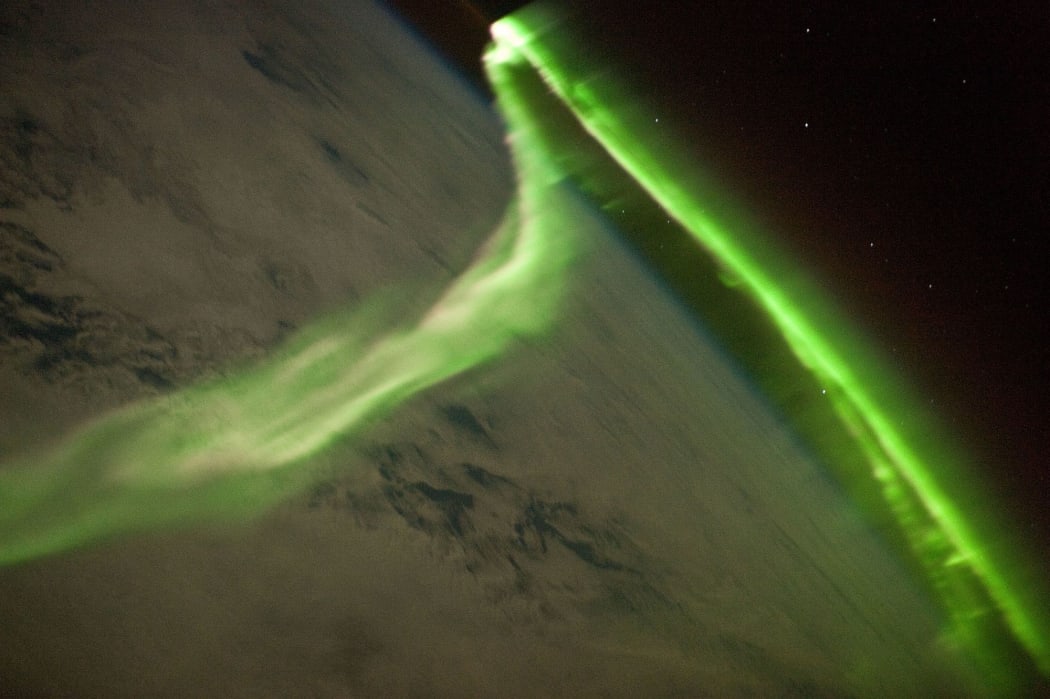 A green Aurora Australis snaking across cloud