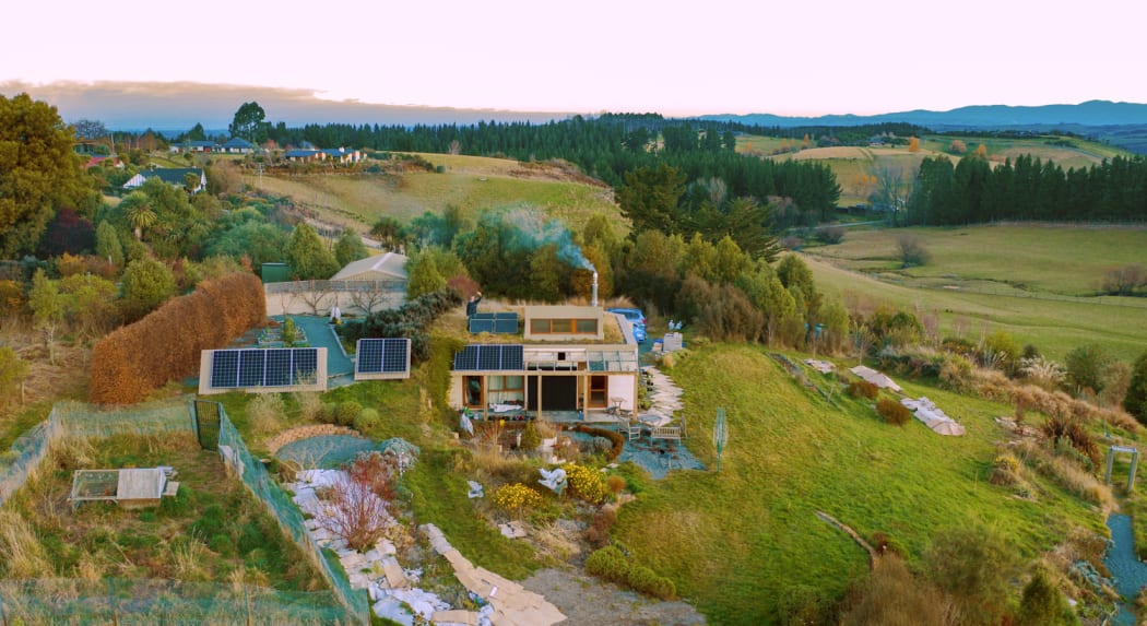 2019 drone view of our house showing solar panels, green roof, on-site-fuelled wood stove in use, chickens enclosure, some of the garden.