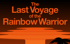 A family gathered on a tropical island, looking towards an orange mushroom cloud at sea.
