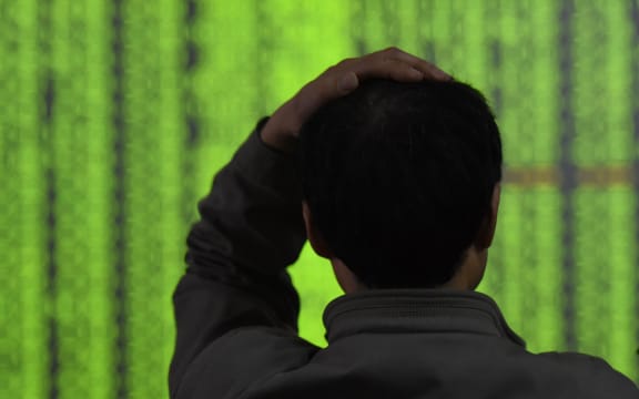 A Chinese investor looks at prices of shares (green for price falling) at a stock brokerage house in Hangzhou city.