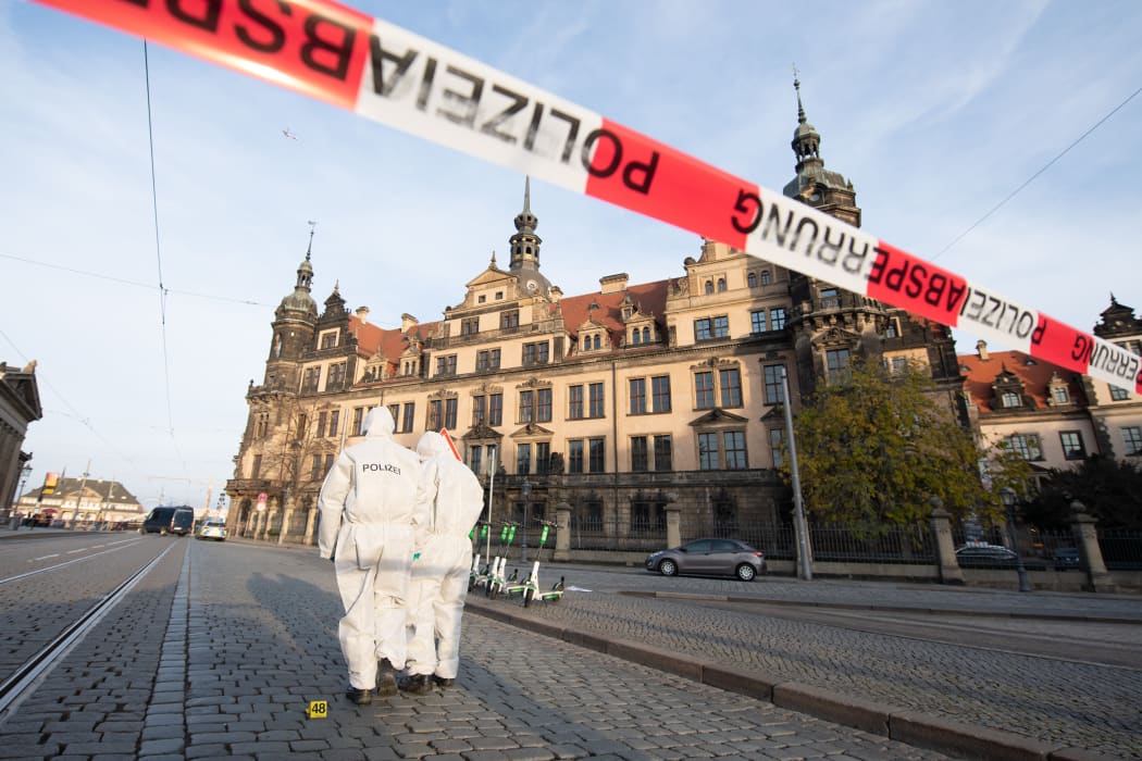 Two police forensic team members stand in front of the Residence Palace with the Green Vault behind a barrier tape. Dresden's Treasury Green Vault was broken into early in the morning.