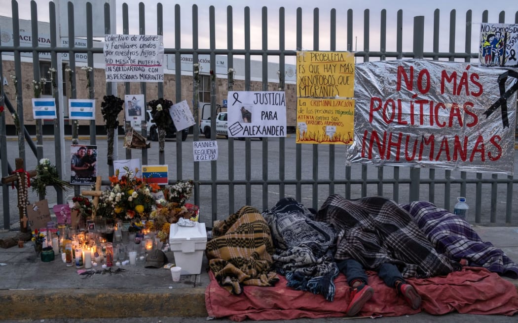 Migrants sleep outside the immigration detention center where 39 migrants died during a fire in Ciudad Juarez, Chihuahua state, Mexico on March 30, 2023. Mexican prosecutors announced a homicide investigation Wednesday into the recent deaths of 39 migrants in a detention center fire, accusing the people in charge of doing nothing to evacuate them. Authorities faced mounting scrutiny of their handling of the disaster after video surveillance footage appeared to show guards leaving as flames engulfed a cell with migrants locked inside. (Photo by Guillermo Arias / AFP)