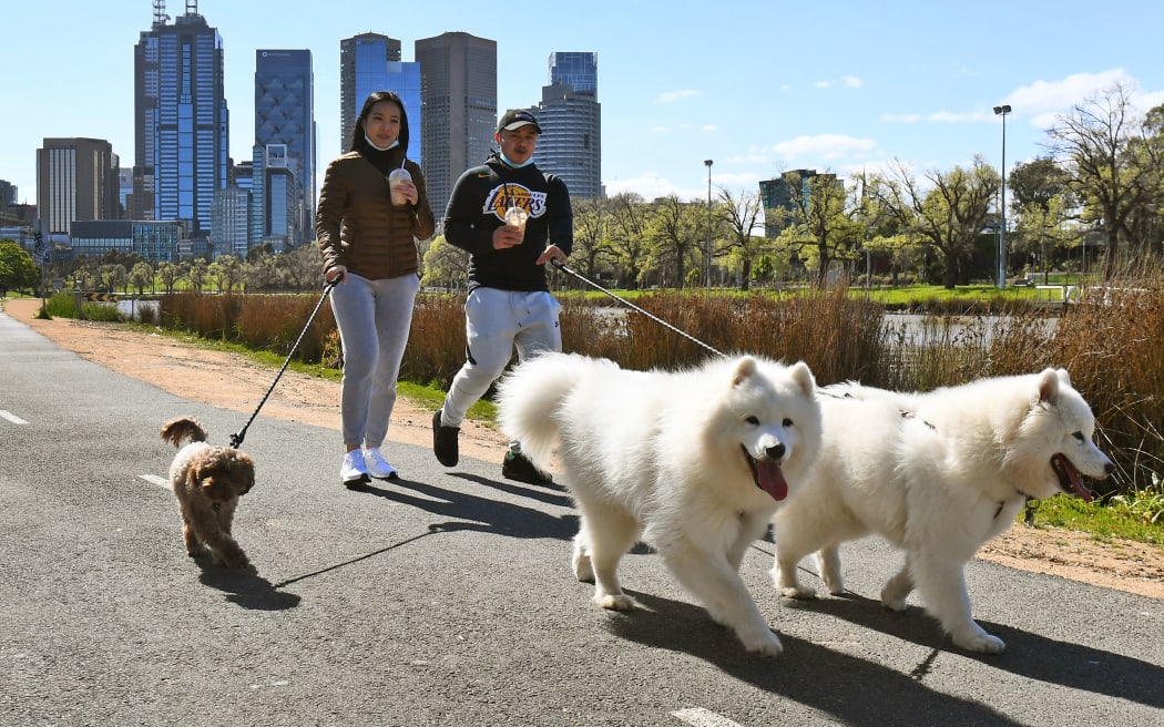 People walk their dogs along the banks of the Yarra River in Melbourne on September 27, 2020 as an overnight curfew in Australia's second-biggest city will be lifted from September 28,