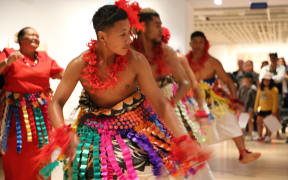 Tongan dancers of the Akomai Heritage Group in costumes made from ngatu, In the background is Melesiu Katoa one of the most experienced ngatu makers in the group.