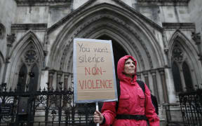 A supporter of climate action group Extinction Rebellion holds a placard outside the Royal Courts of Justice that houses the High Court in London on 24 October, 2019.